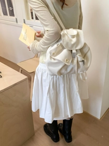 Minimalist white canvas backpack for women shown worn on back in a modern interior setting