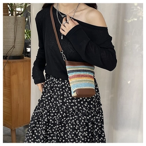 Detail of colorful striped knit crossbody bag with leather trim on model