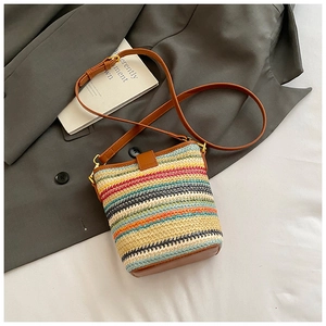 Detailed view of woven rainbow stripe bucket bag with brown leather strap and gold hardware