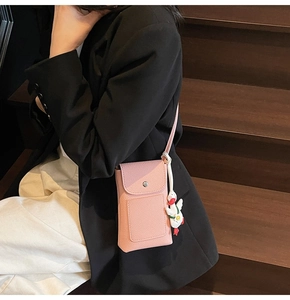 Pink lychee grain leather phone bag with cute white goose charm on wooden stairs