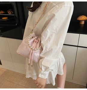 Détail du sac seau rose avec broderie papillon, poignée en perles et bandoulière