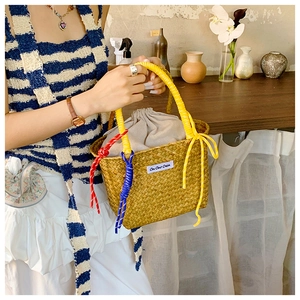 Detail of hand-woven straw bag featuring yellow handles and cotton drawstring liner