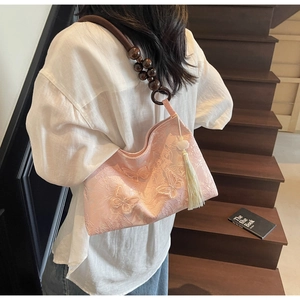 Détail du sac papillon brodé rose avec bandoulière en bois et pompon blanc élégant