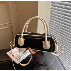 Detail of minimalist black and white cylinder bag with premium PU texture and silver hardware