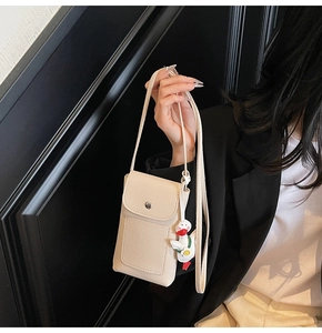 Detail of cream crossbody phone bag with litchi grain leather and a cute duck pendant