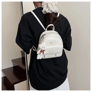 Detailed back view of a white mini PU leather backpack with plush bear charm on a model