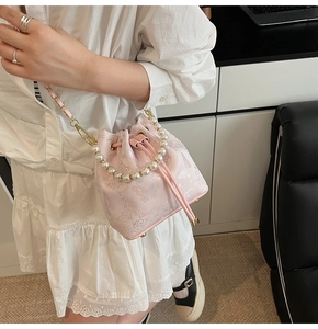 Détail du sac seau rose brodé avec poignée en perles et bandoulière chaîne