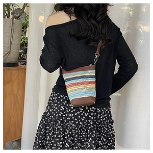 Detail of bohemian striped woven bucket bag with brown leather trim and metal hooks