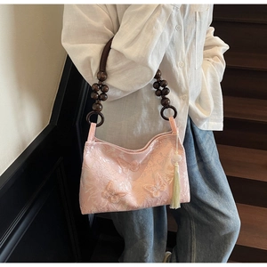 Détail du sac jacquard rose avec poignée en bois perlé et pendentif à pompon