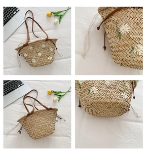 Detail of straw tote bag featuring white daisy embroidery and leather straps for summer