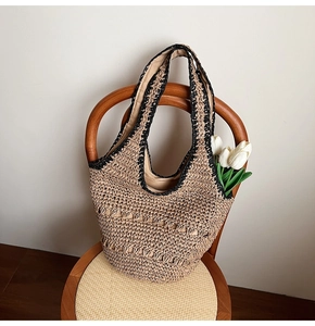 Detail of woven straw tote bag with black trim and interior fabric lining on a chair