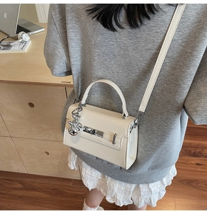 Detail of off-white leather Kelly style handbag with silver hardware and rabbit charm