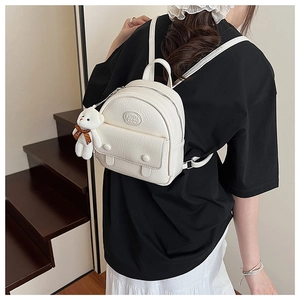 Detail view of mini cream backpack with pleated texture and cute white bear charm