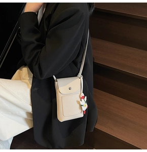 Detail of beige lychee textured crossbody phone bag with cute duck charm and silver buckle