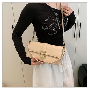 Détail d'un sac à bandoulière beige avec boucle métallique dorée en D et bandoulière fine