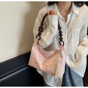 Détail du sac en jacquard floral avec broderie papillon rose et poignée en bois