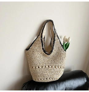 Detail of woven straw tote bag featuring black crochet trim and hollow wave patterns