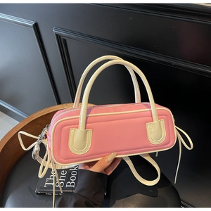 Close-up of pink baguette bag with white handles and stylish side tassel detail