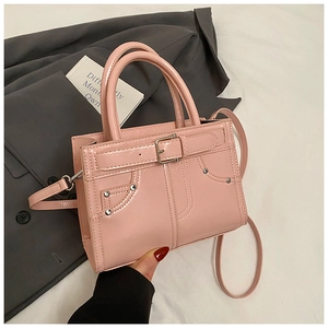 Détail du sac à main rose en cuir verni avec clous métalliques et boucles