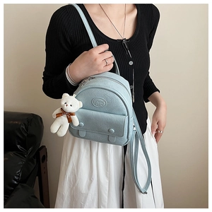 Detail view of light blue mini backpack with crinkle texture and plush bear charm