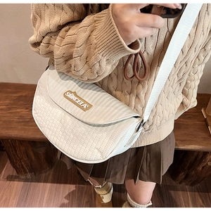 Detail of white quilted saddle bag with wide shoulder strap and SINCELA brand plaque