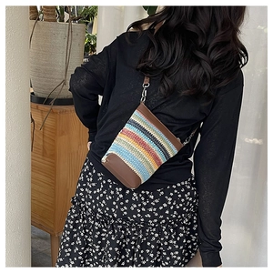 Detail of woven striped crossbody bag with leather trim and adjustable shoulder strap