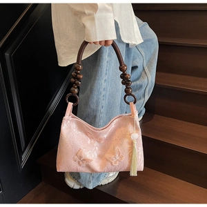 Détail d'un sac rose en dentelle avec papillons 3D et poignées en perles de bois