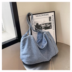 Detail of light blue denim hobo bag featuring decorative metal rivets and soft fabric