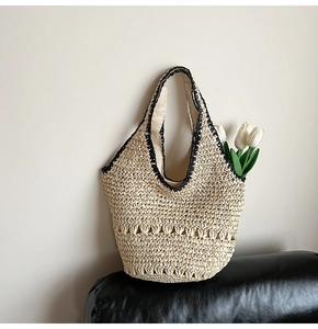 Close-up of handmade woven straw bag with black contrast crochet trim and hollow texture