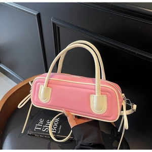 Close-up of pink leather bag with cream trim and elegant ribbon detail on the side