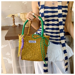 Detail of woven straw bucket bag with colorful braided handles in a summer setting