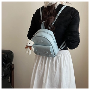 Detail of light blue mini backpack in textured PU leather with a cute bear charm pendant