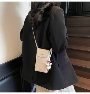Detail of beige textured leather mini crossbody bag with a cute white duck charm accessory