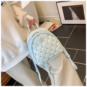 Detailed close-up of light blue quilted mini backpack with silver rivets and star decor