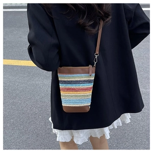 Detail of colorful woven bucket bag with brown leather trim and silver metal hardware