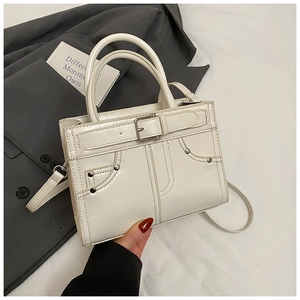 Vue détaillée du sac à main blanc crème avec boucle de ceinture et coutures à rivets