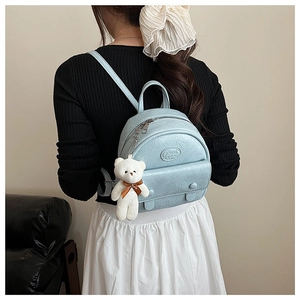 Close-up of light blue mini backpack in retro wrinkled leather with white plush bear charm