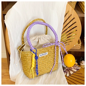 Detail view of handmade straw bucket bag with purple woven handle and drawstring liner