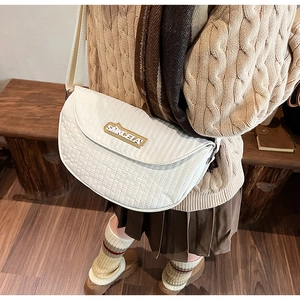 Close-up of white quilted half-moon crossbody bag with wide strap worn by a model