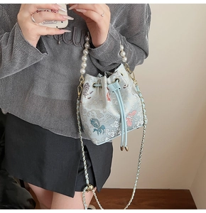 Détail d'un sac seau brodé bleu clair avec anse en perles et motifs traditionnels