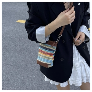 Detail of colorful woven phone bag with brown leather trim and adjustable strap