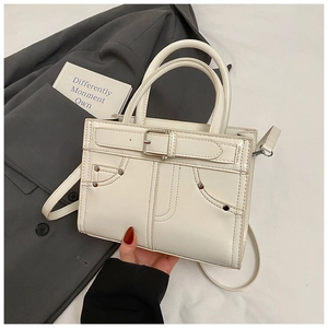 Détail d'un sac à main blanc avec décor de poche en jean et poignées rondes