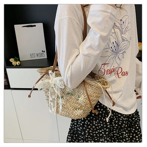 Detail of straw bucket bag with white daisy embroidery and lace bow for summer beach style
