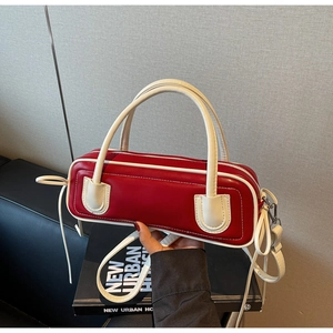 Detail of red and cream contrast leather baguette bag featuring side drawstring accents