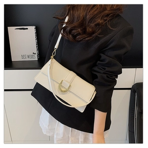 Détail du sac bandoulière crème avec boucle fer à cheval dorée et sa lanière