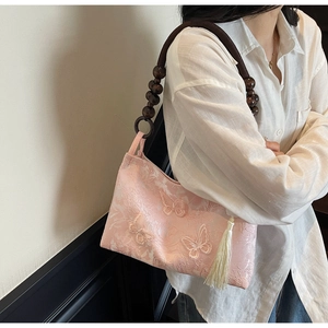 Détail du sac cabas papillon rose avec lanières en perles de bois et franges blanches