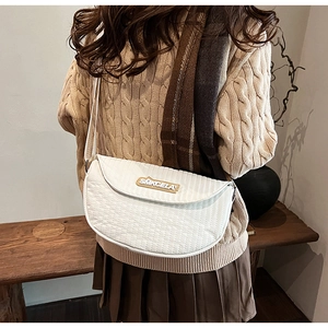 Detailed view of white quilted crescent bag with gold logo and vertical stitch pattern