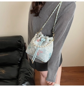 Détail du sac seau brodé vert menthe avec anse en perles et motif floral chinois