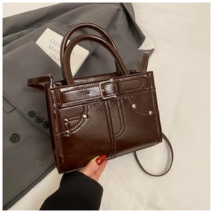 Détail du sac à bandoulière vintage marron foncé avec rivets et similicuir poli