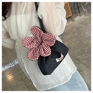 Detail of denim crossbody bag featuring a large red gingham flower and Yes Honey label